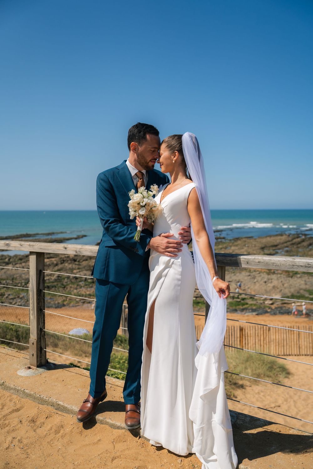 Coastal wedding photoshoot with scenic ocean views and sandy dunes in the background.