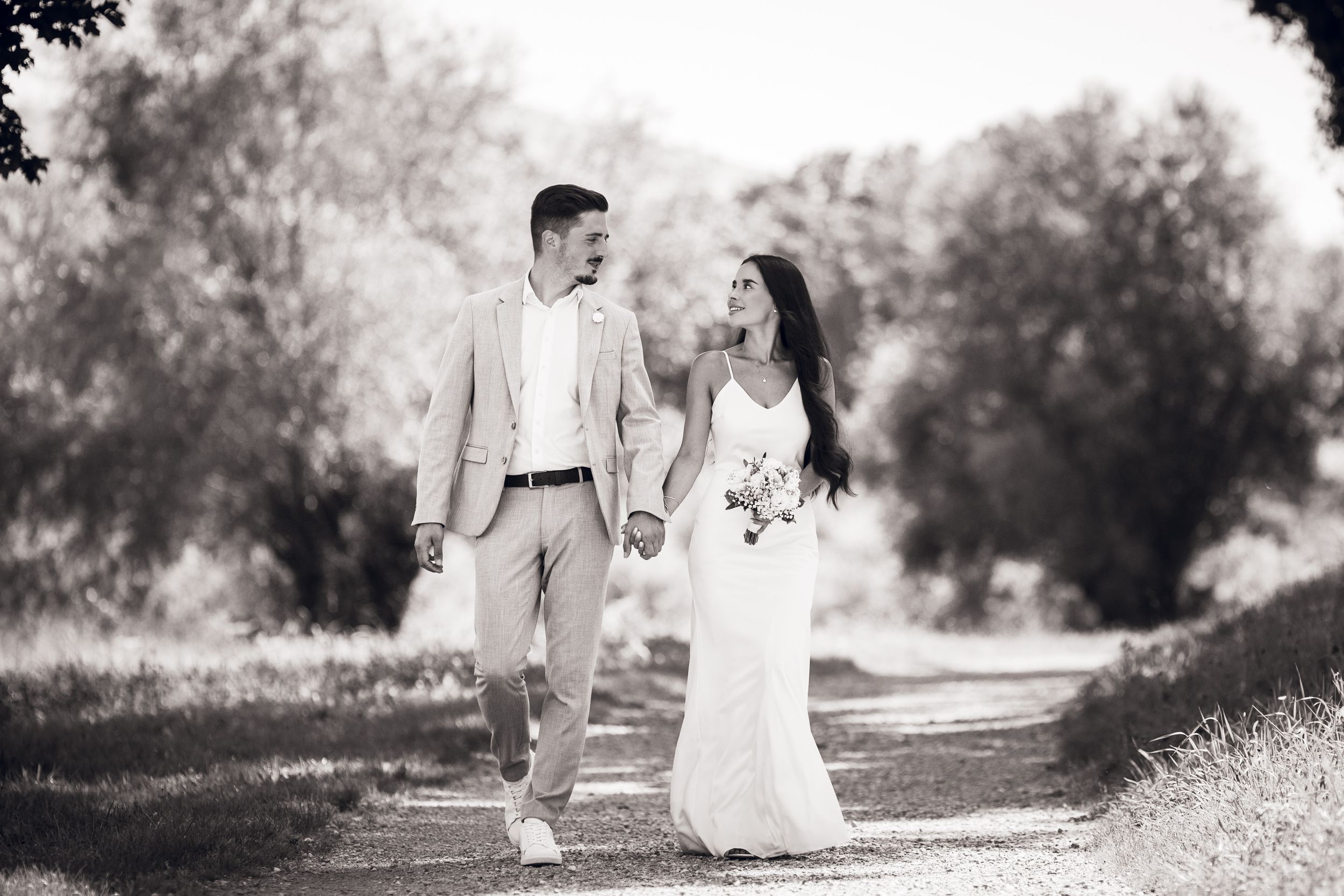 Romantic black and white photo series showing a couple walking together on a scenic outdoor path.