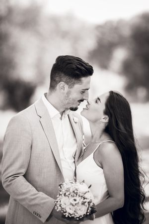 Black and white romantic wedding portrait series showing a couple sharing tender kisses and embraces outdoors.