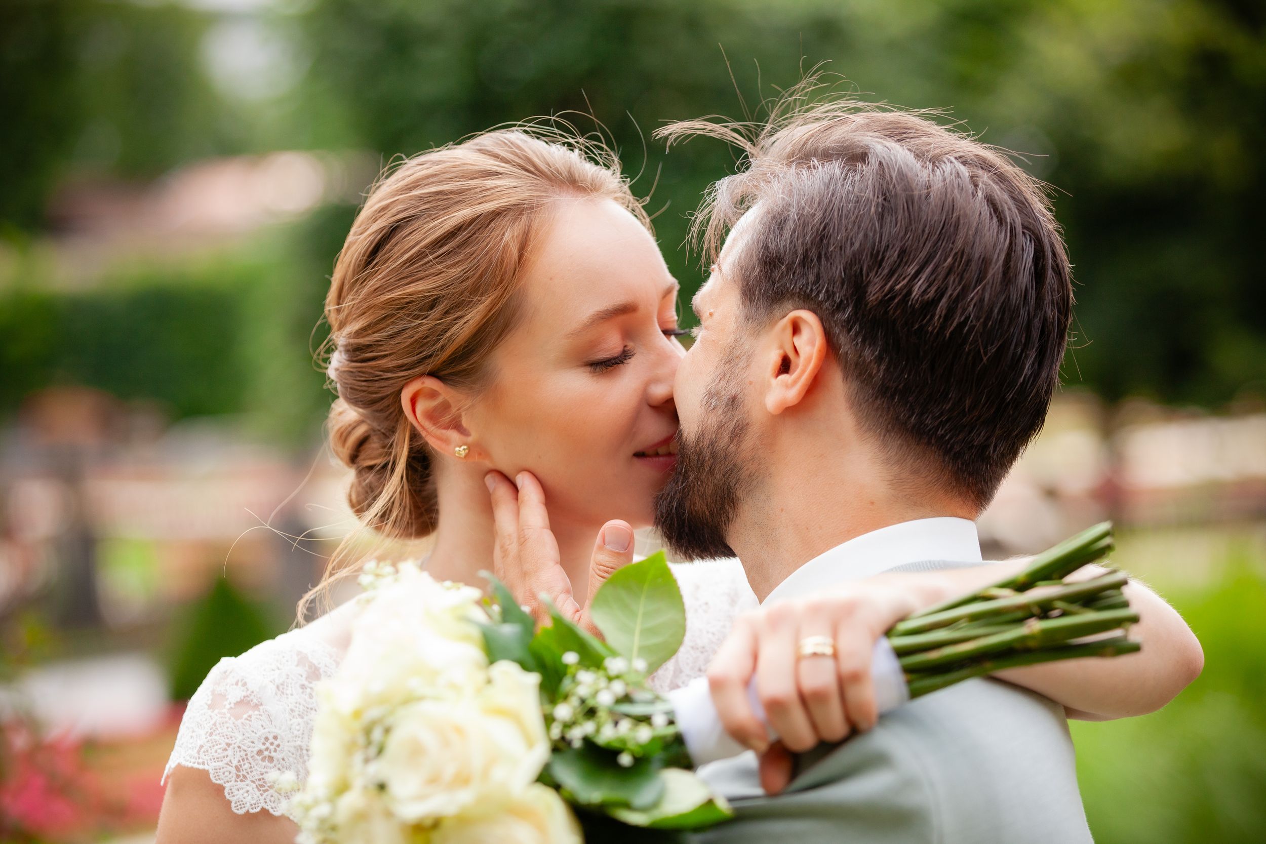 Wedding couple shares an intimate moment in a lush garden setting during their celebration.