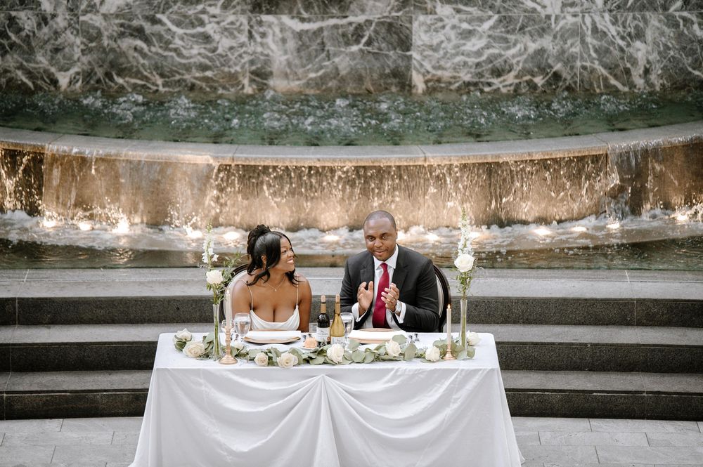 Overhead view of elegantly set wedding tables on garden terrace with white tablecloths and floral centerpieces.