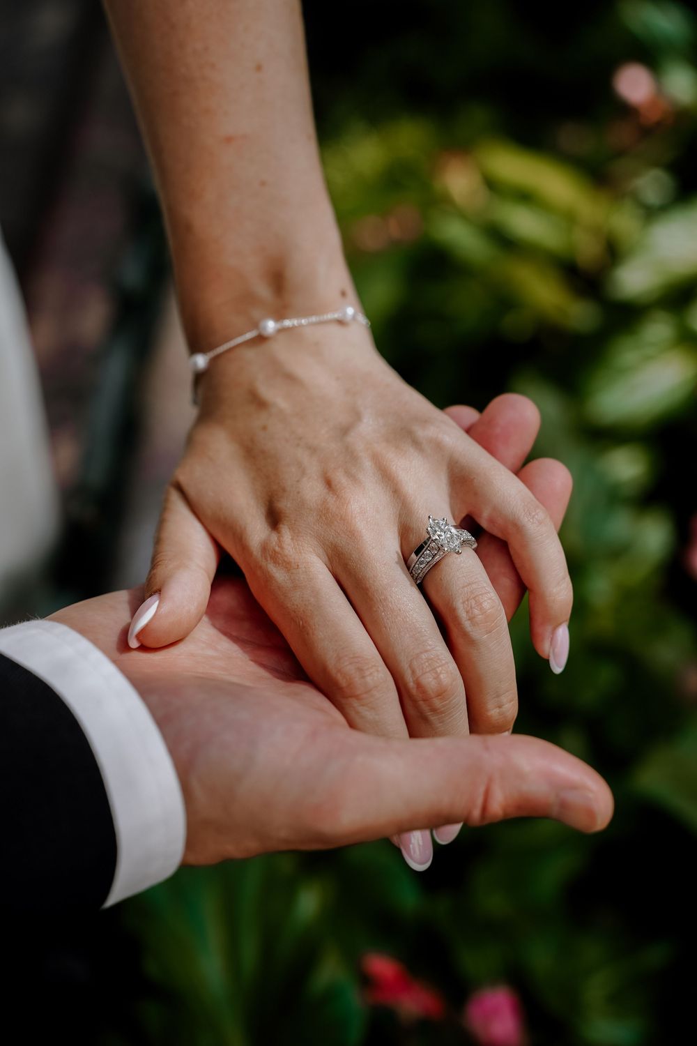 Close-up series of hands holding each other with an engagement ring, showing romantic connection in a garden setting.
