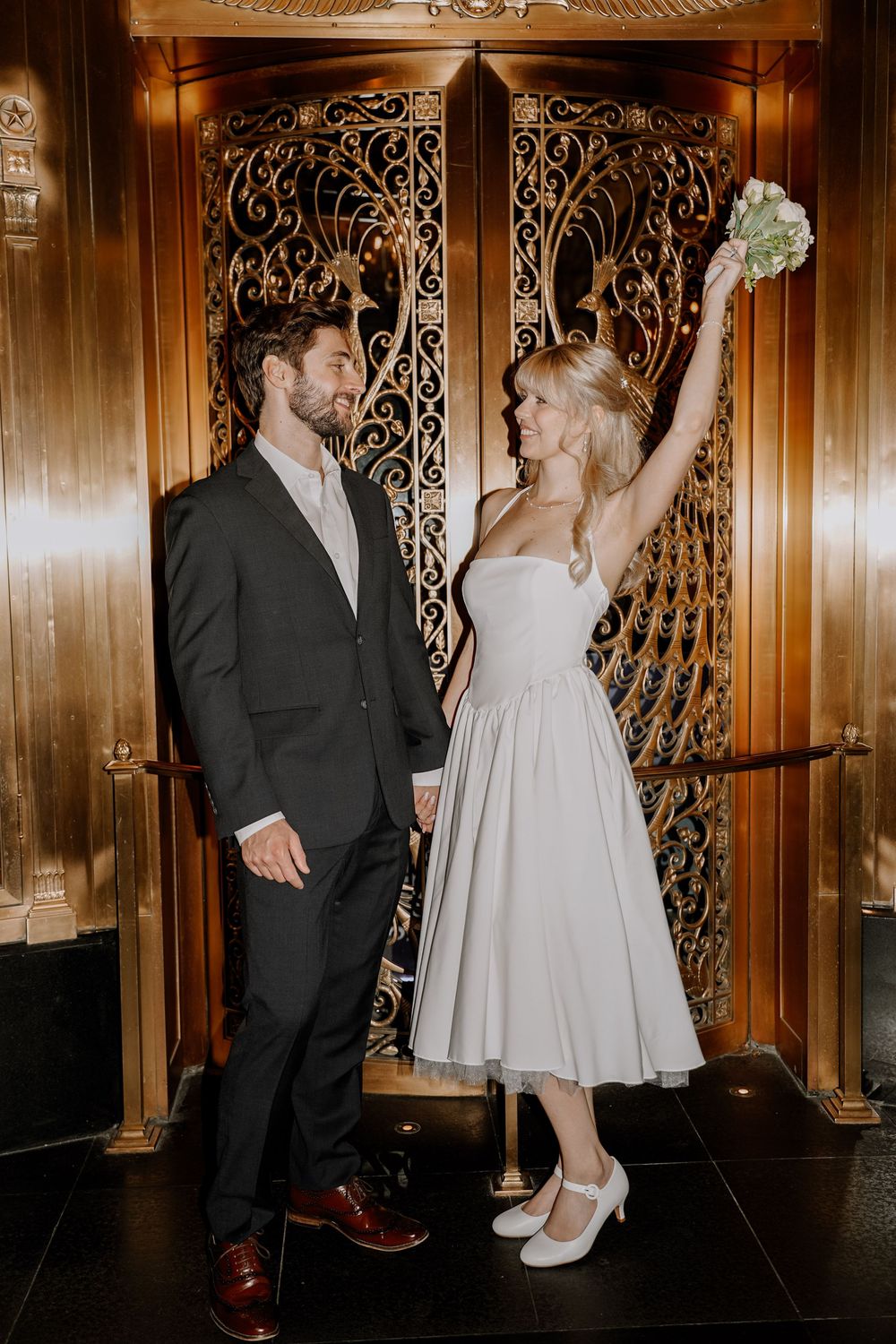 A couple in formal attire dances together in an elegant wood-paneled room with ornate decorative details.