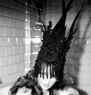 Black and white photograph showing Jessica Wilcock wearing a head dress by Jay Briggs Millinery