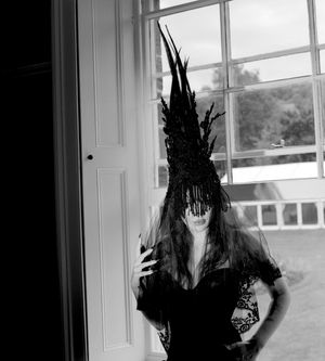 Black and white photograph showing Jessica Wilcock wearing a head dress by Jay Briggs Millinery