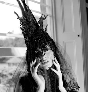 Black and white photograph showing Jessica Wilcock wearing a head dress by Jay Briggs Millinery