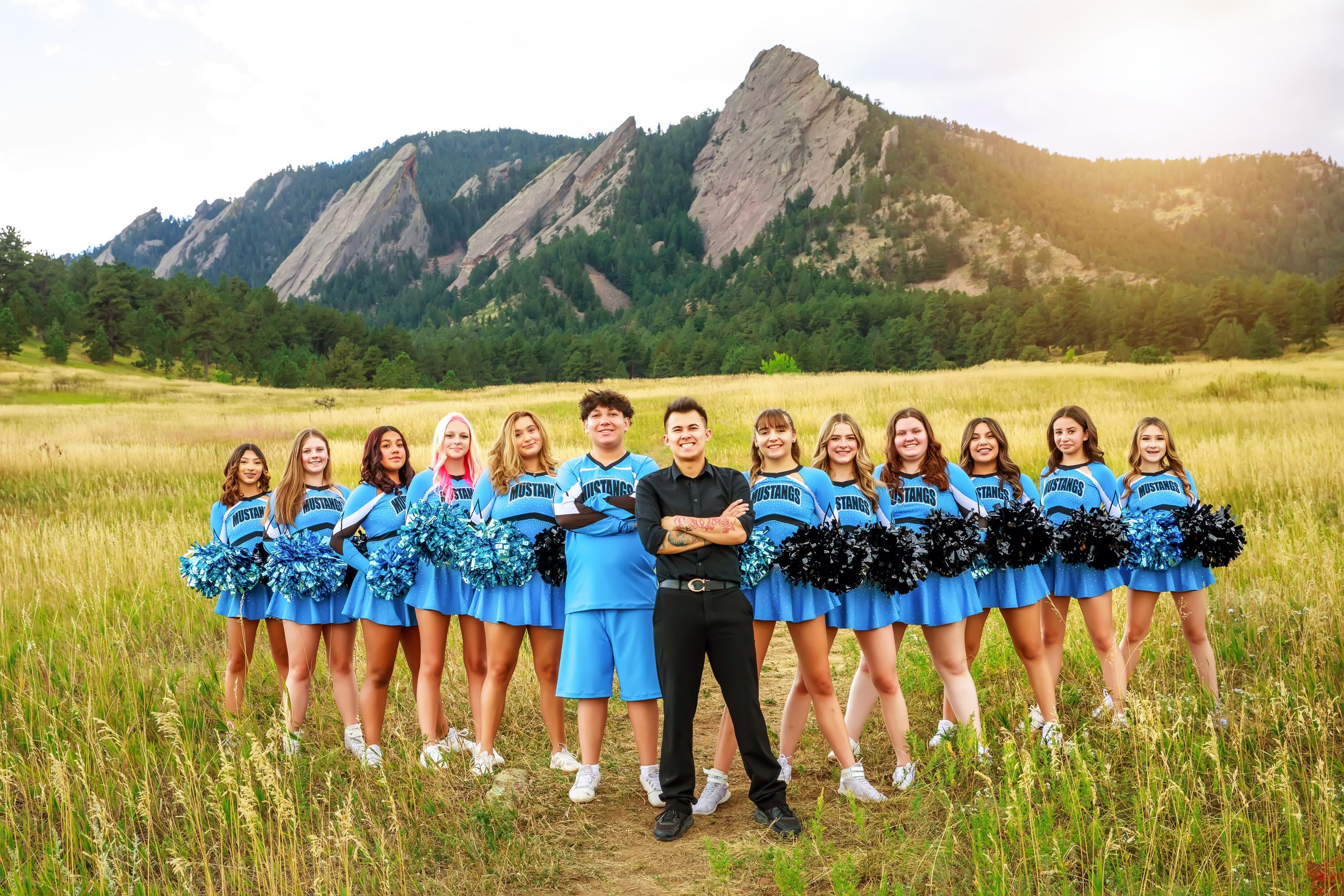 A panoramic collage showing a group posed in various arrangements against a scenic mountain backdrop and grasslands.