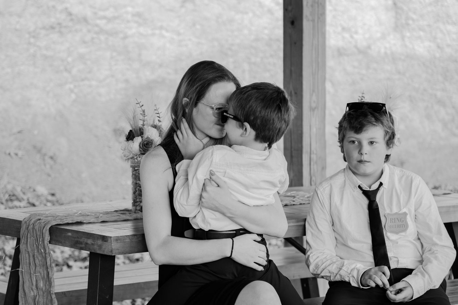 A black and white wedding photo series showing candid moments between guests and the wedding party.