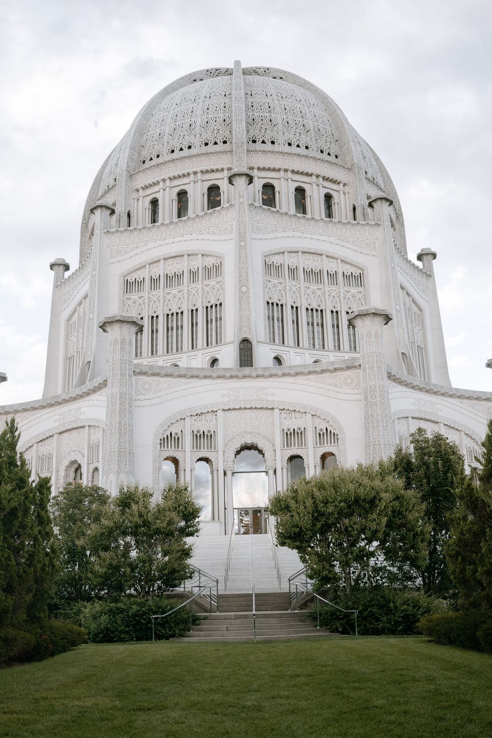 White dome of the Baha'i House of Worship rises majestically against cloudy skies in a series of architectural views.