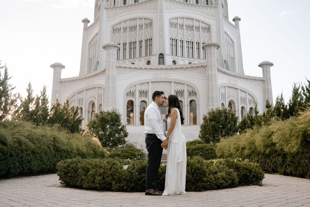 A Baha'i Temple surrounded by greenery with dramatic white domed architecture and ornate details stands majestically.