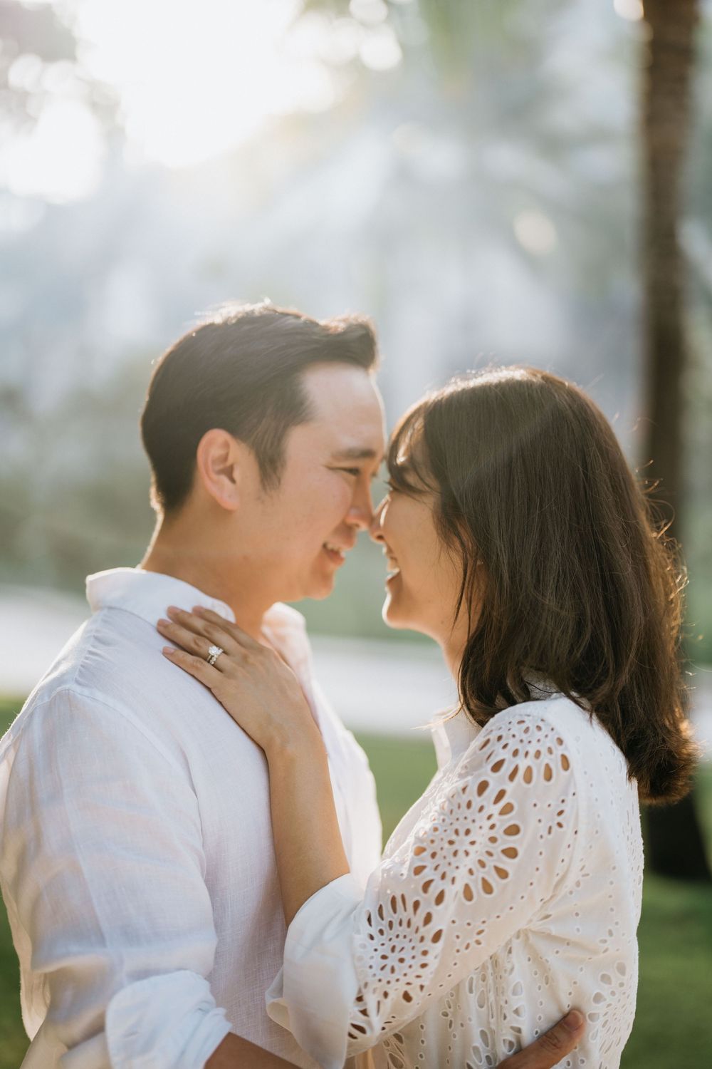 Intimate couple sharing a tender moment in a sunlit tropical garden.