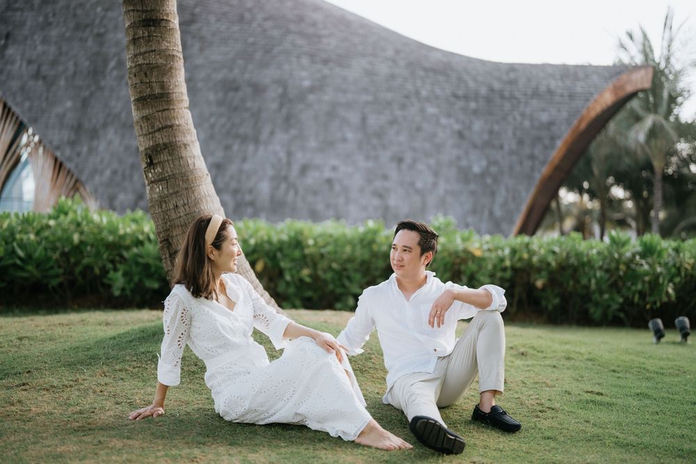 Couple relaxing on manicured lawn with curved architectural structure behind.