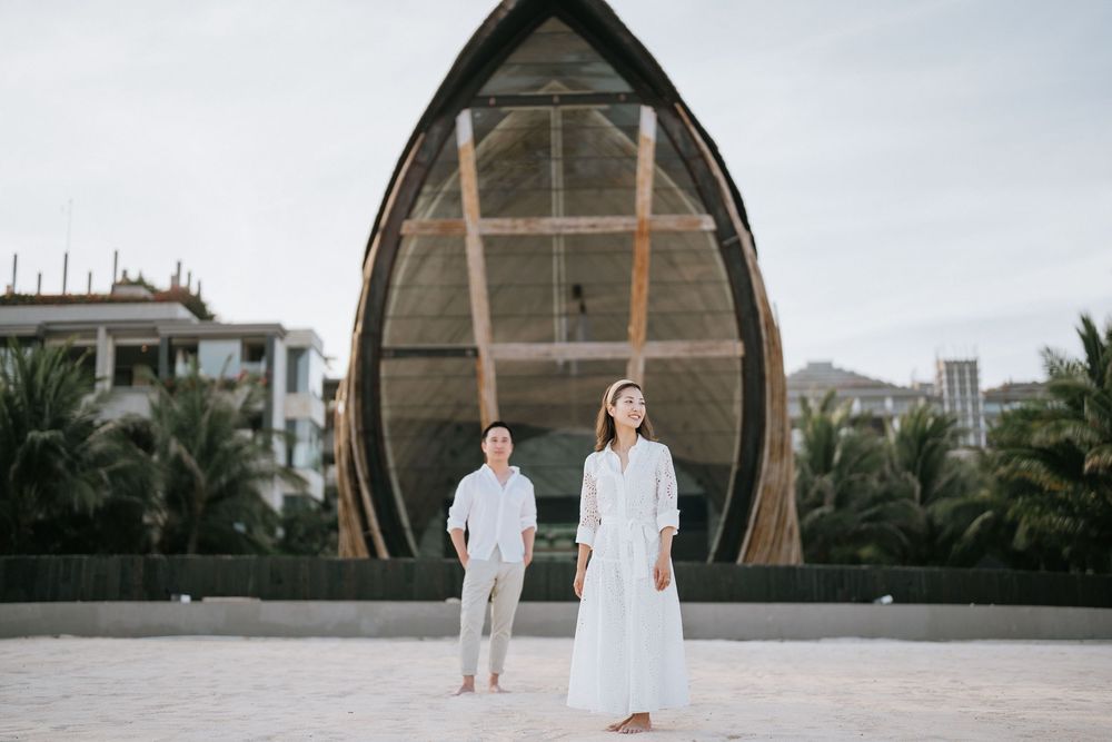 Couple posing in front of dramatic boat-shaped chapel architecture.