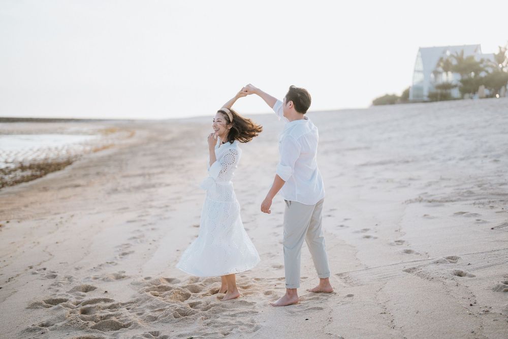 Two people dancing together on a beach with palm trees in the background.