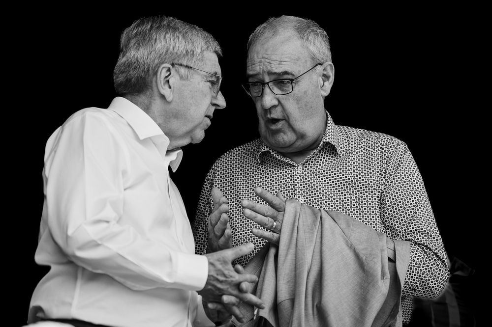Two elderly friends sitting next to each other engage in an animated conversation while sharing ice cream cones.
