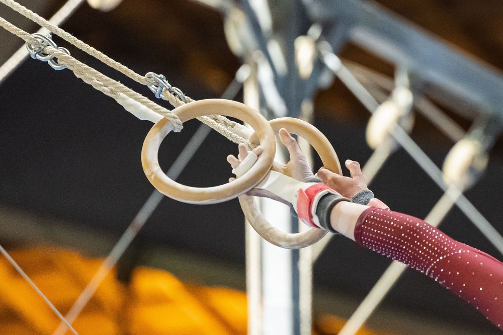 Close-up view of gymnastic rings attached to cables in a fitness or training facility.