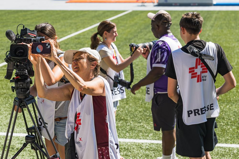 Camera operators and photographers with professional equipment filming an outdoor event.
