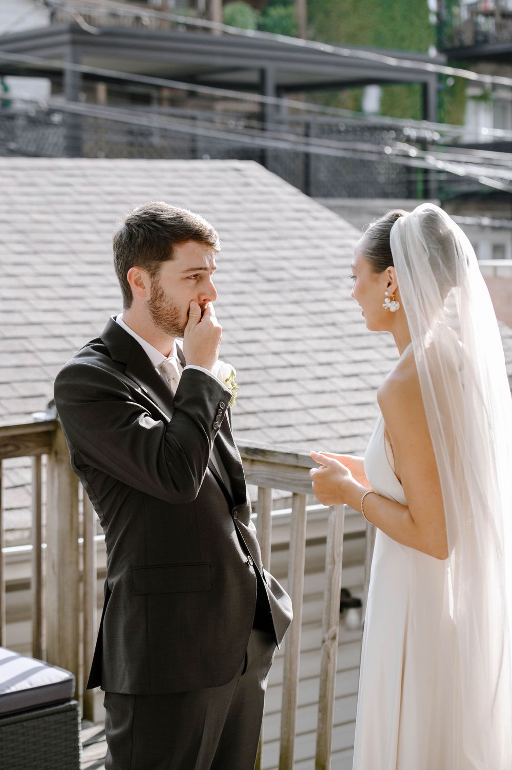 A couple shares an emotional first look moment on their wedding day on an outdoor deck.