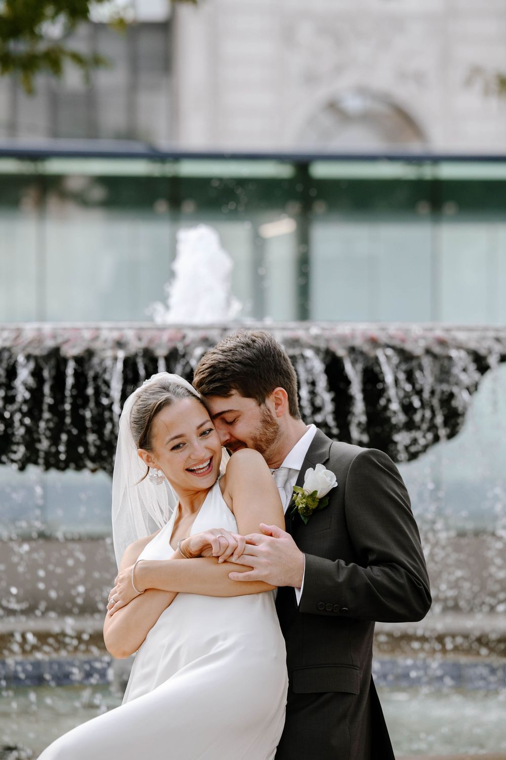 A romantic moment between newlyweds near a fountain on their wedding day.