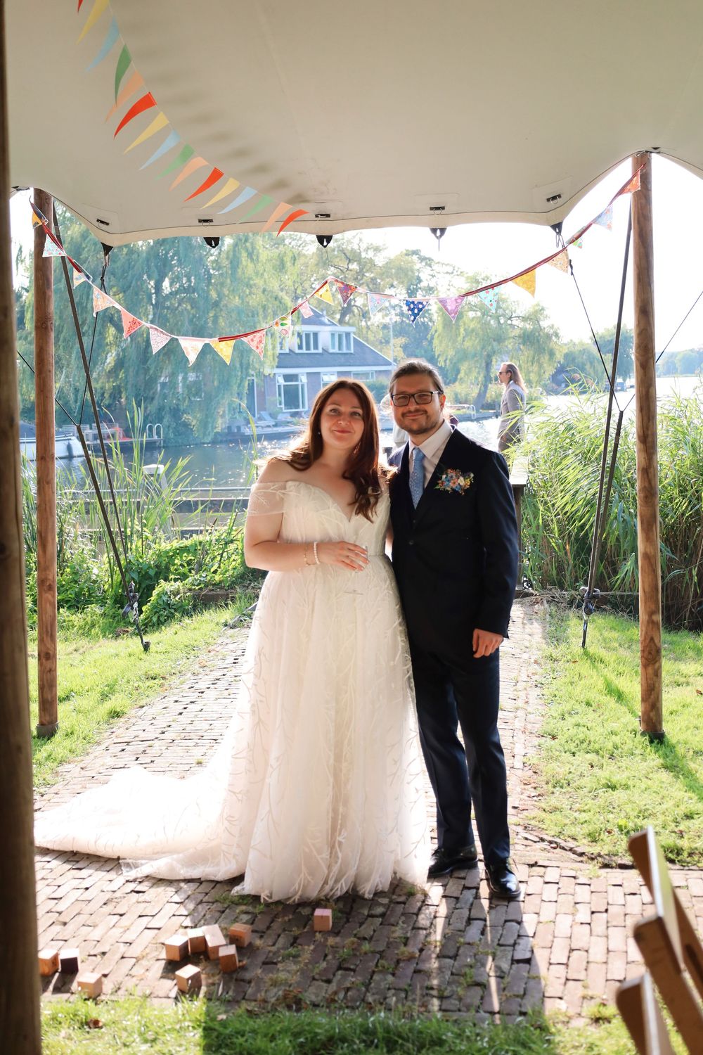 A wedding celebration under colorful bunting flags with a waterfront backdrop.