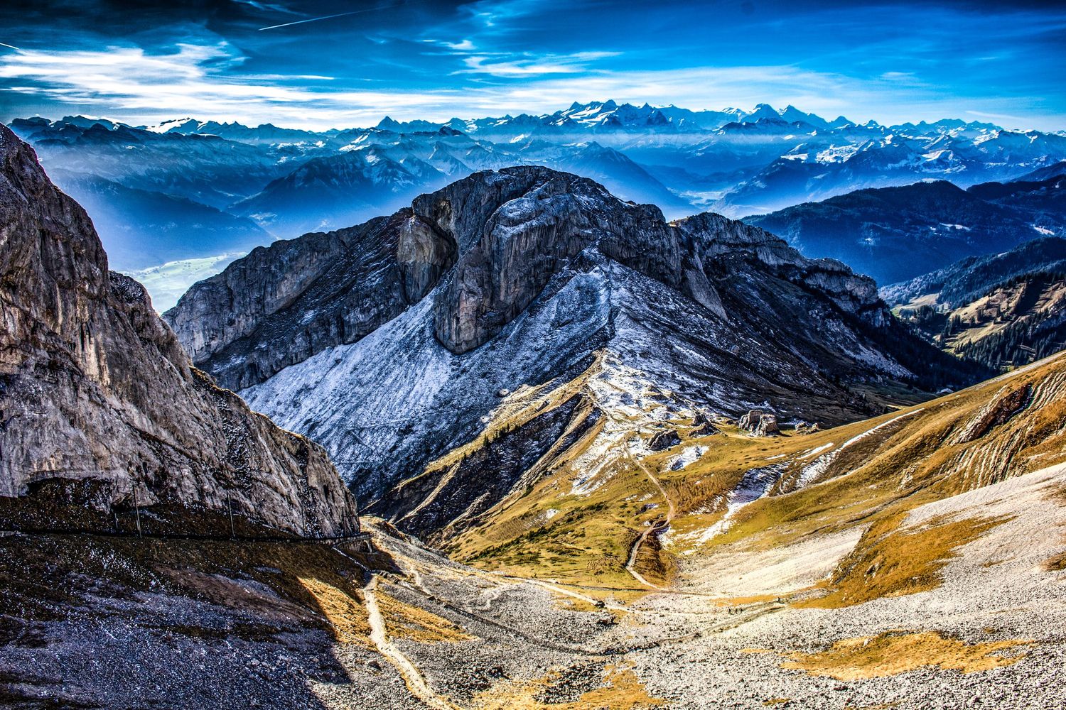 Breathtaking aerial view of rugged Alpine mountain peaks and valleys with misty blue sky in Switzerland.