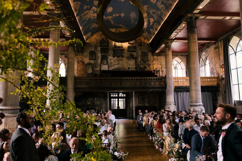 Reception venue decorated with string lights and greenery showing multiple banquet tables in a rustic indoor setting.