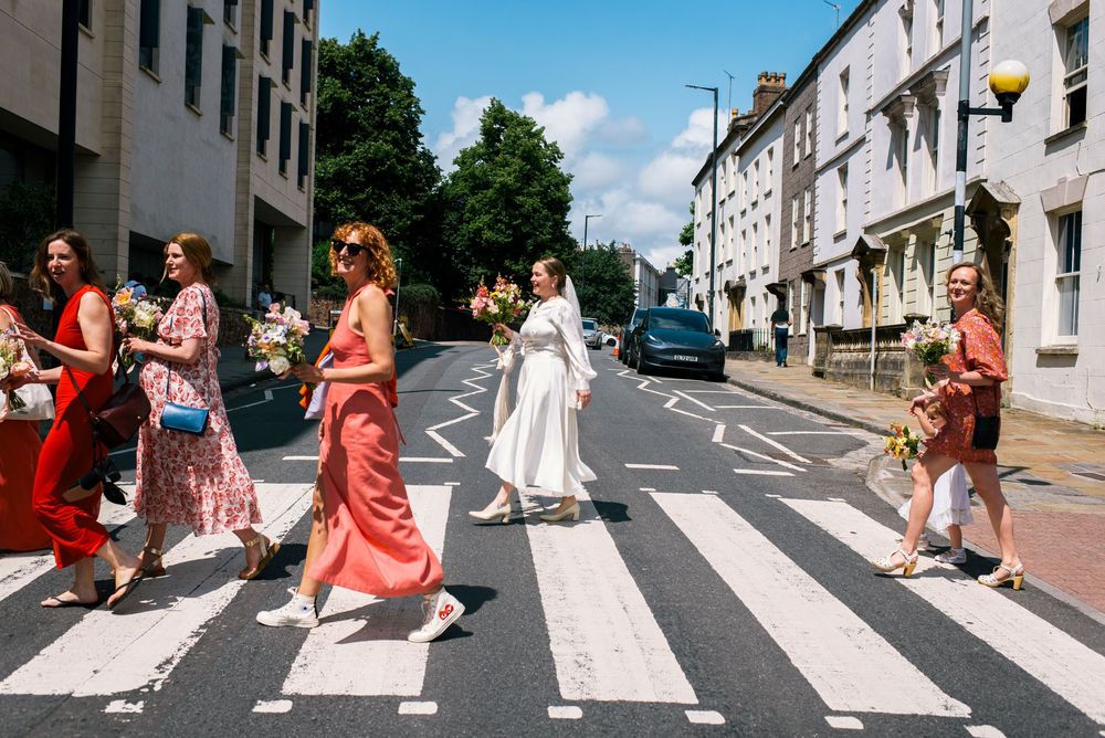 Wedding party recreates the iconic Beatles Abbey Road album cover photo walking across a street.