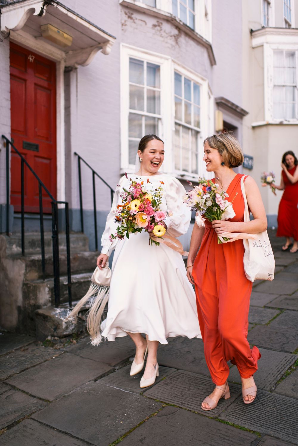 People walking on historic street carrying colorful flower bouquets.