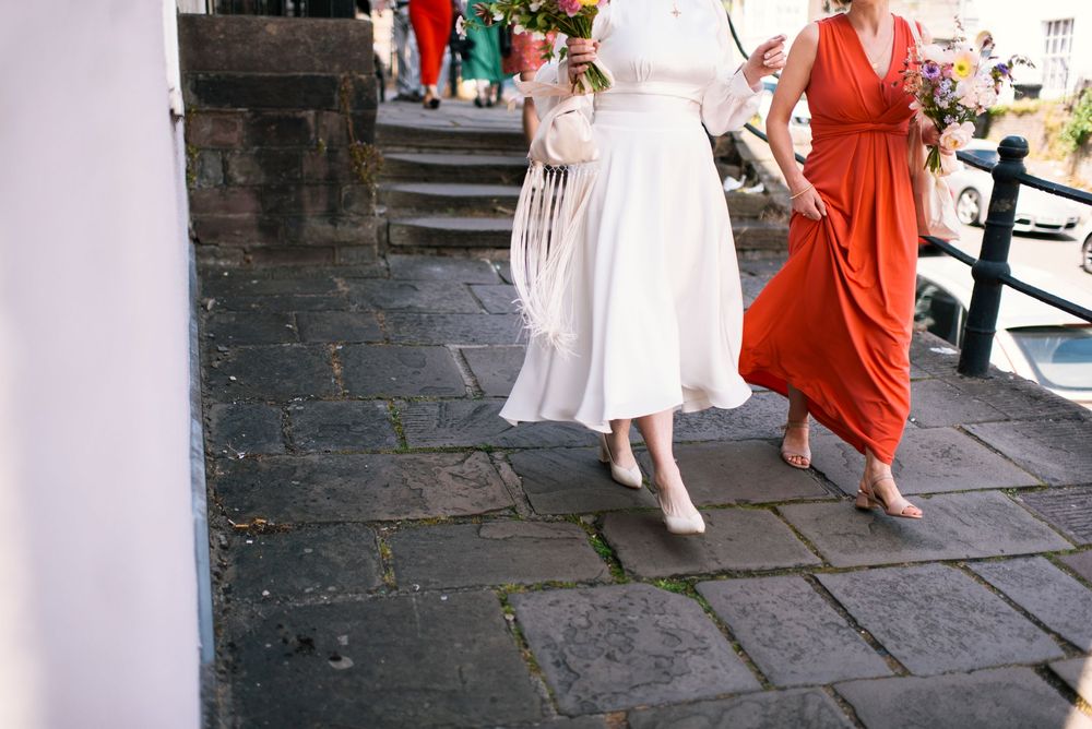 Guests in white and red attire mingle during an outdoor celebration on a stone patio.
