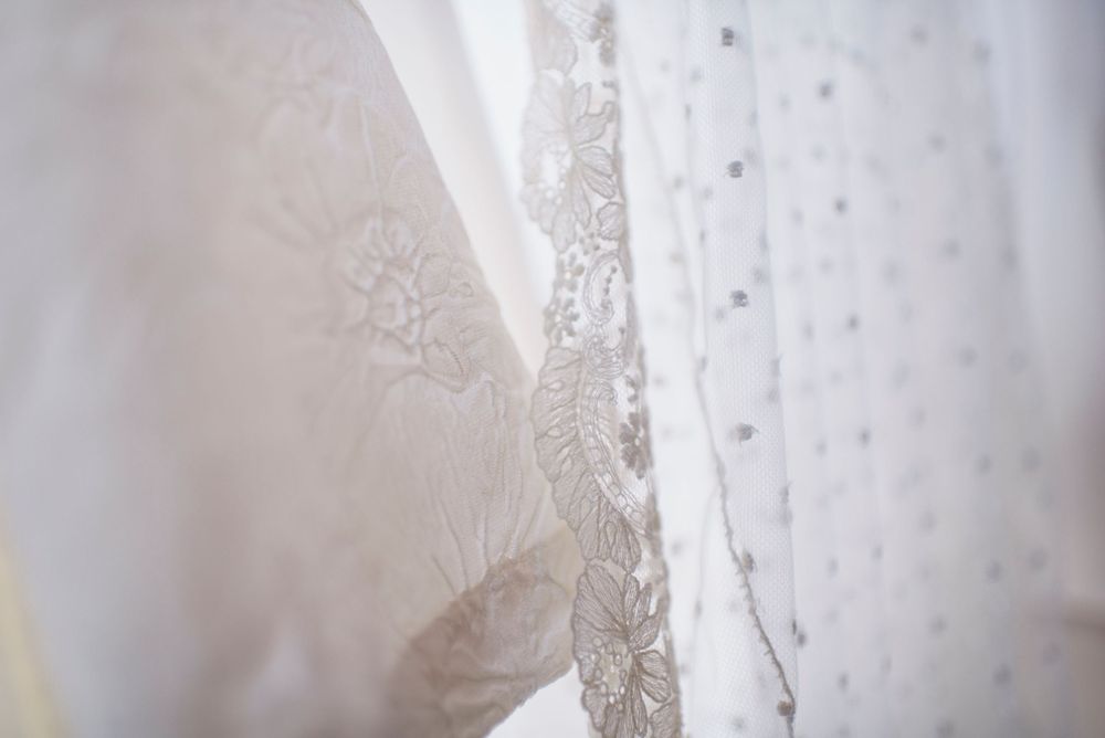 Close-up detail of delicate lace pattern on white wedding dress fabric.