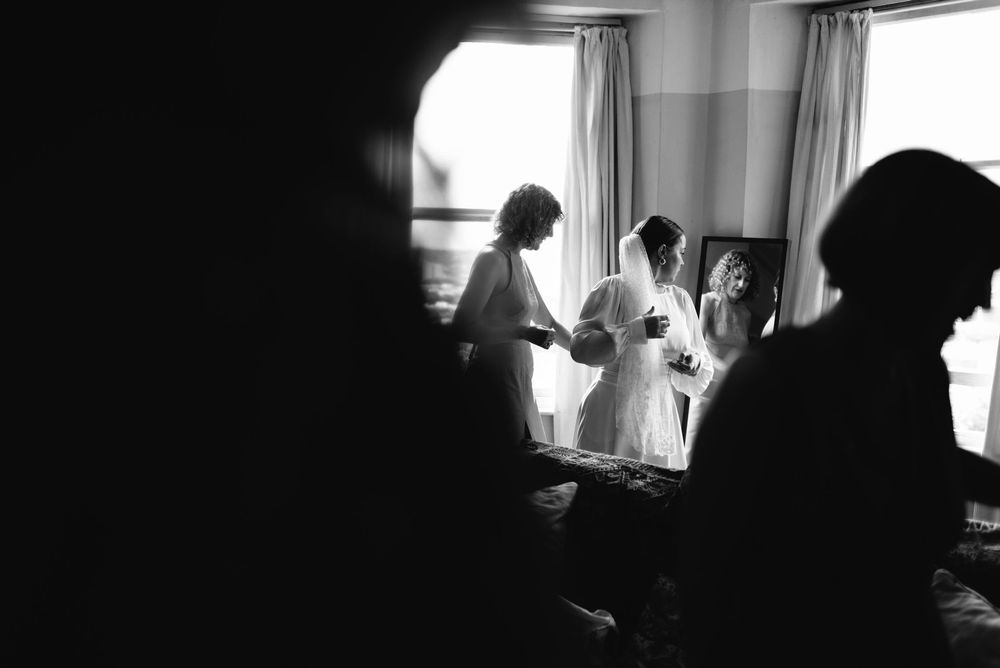 Black and white silhouettes of people by windows in a dim interior room.