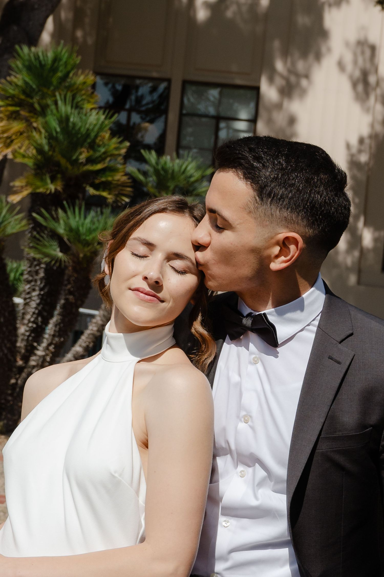 Elopement at the San Diego County Clerks office, couple standing in front of building, husband kissing wife's forehead.