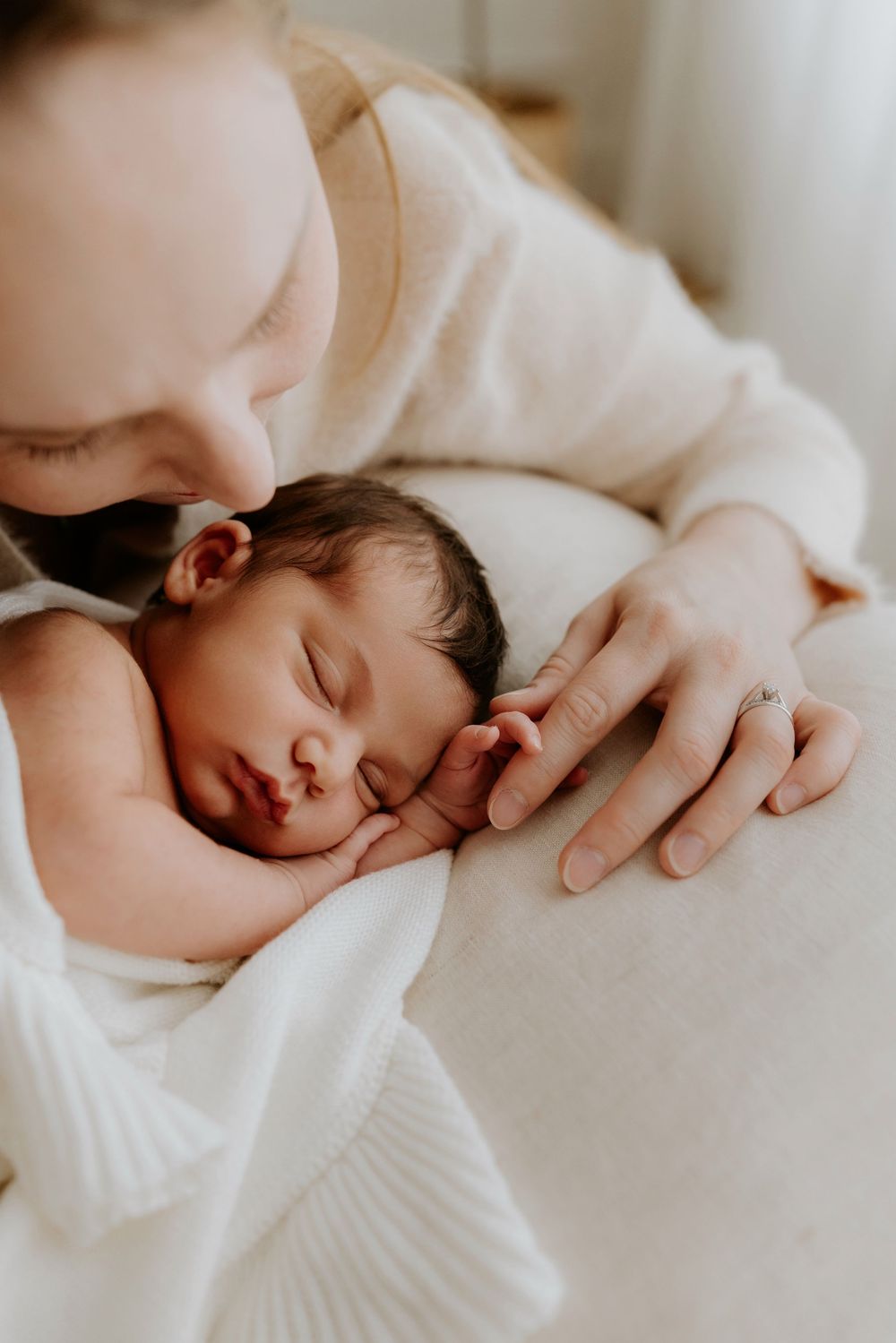 Adelaide baby photographer Lauren Lunn captures mum gazing at her sleeping newborn in neutral blankets during their photography session.