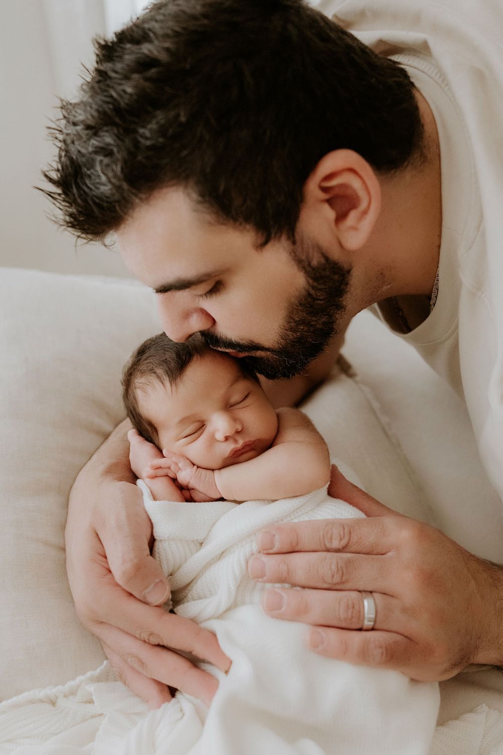 Dad kisses and cradles his gorgeous newborn baby during Adelaide photo session with Lauren Lunn Photography at their home studio.