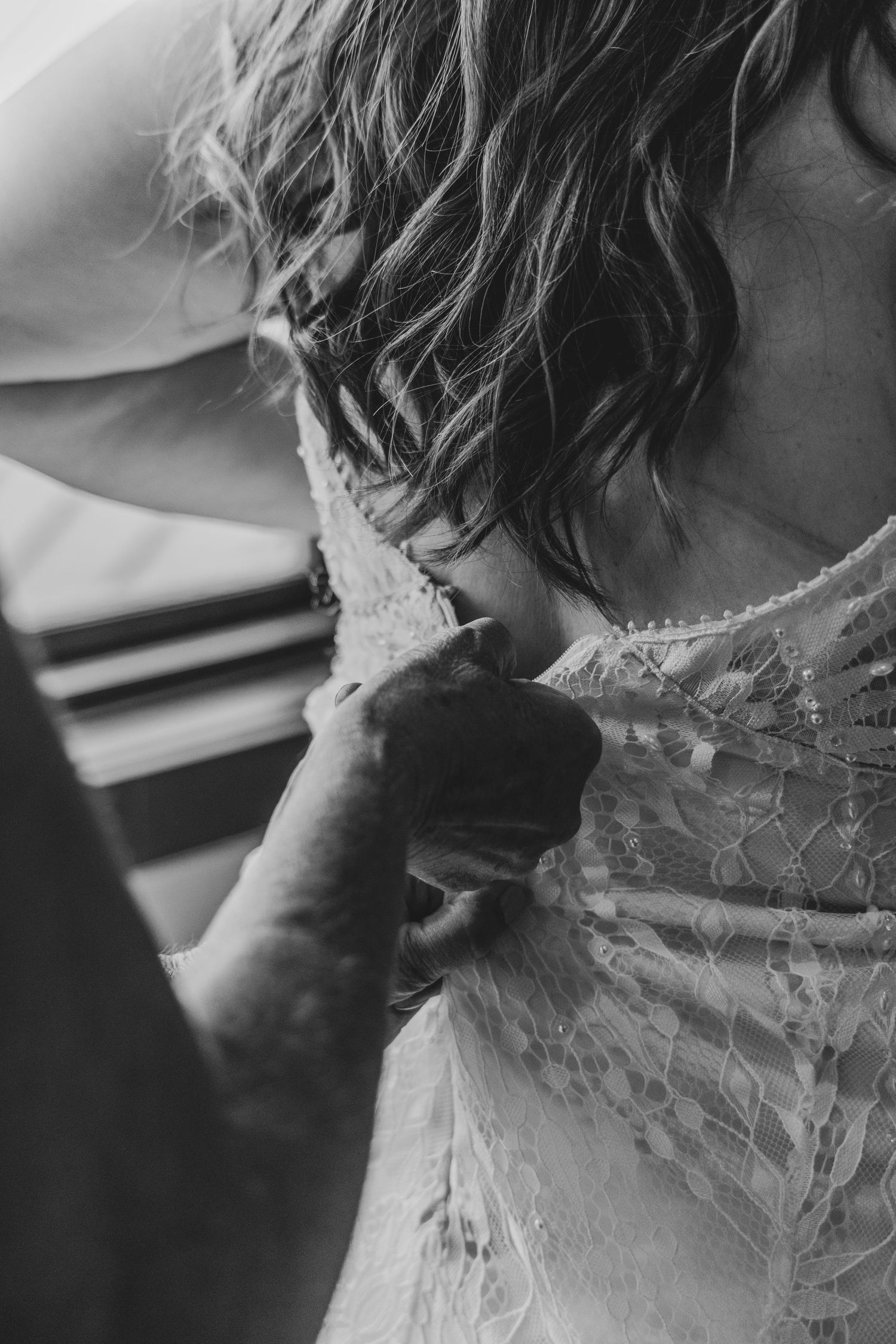 A series of black and white photographs showing closeup details of an elegant lace wedding dress with intricate patterns.