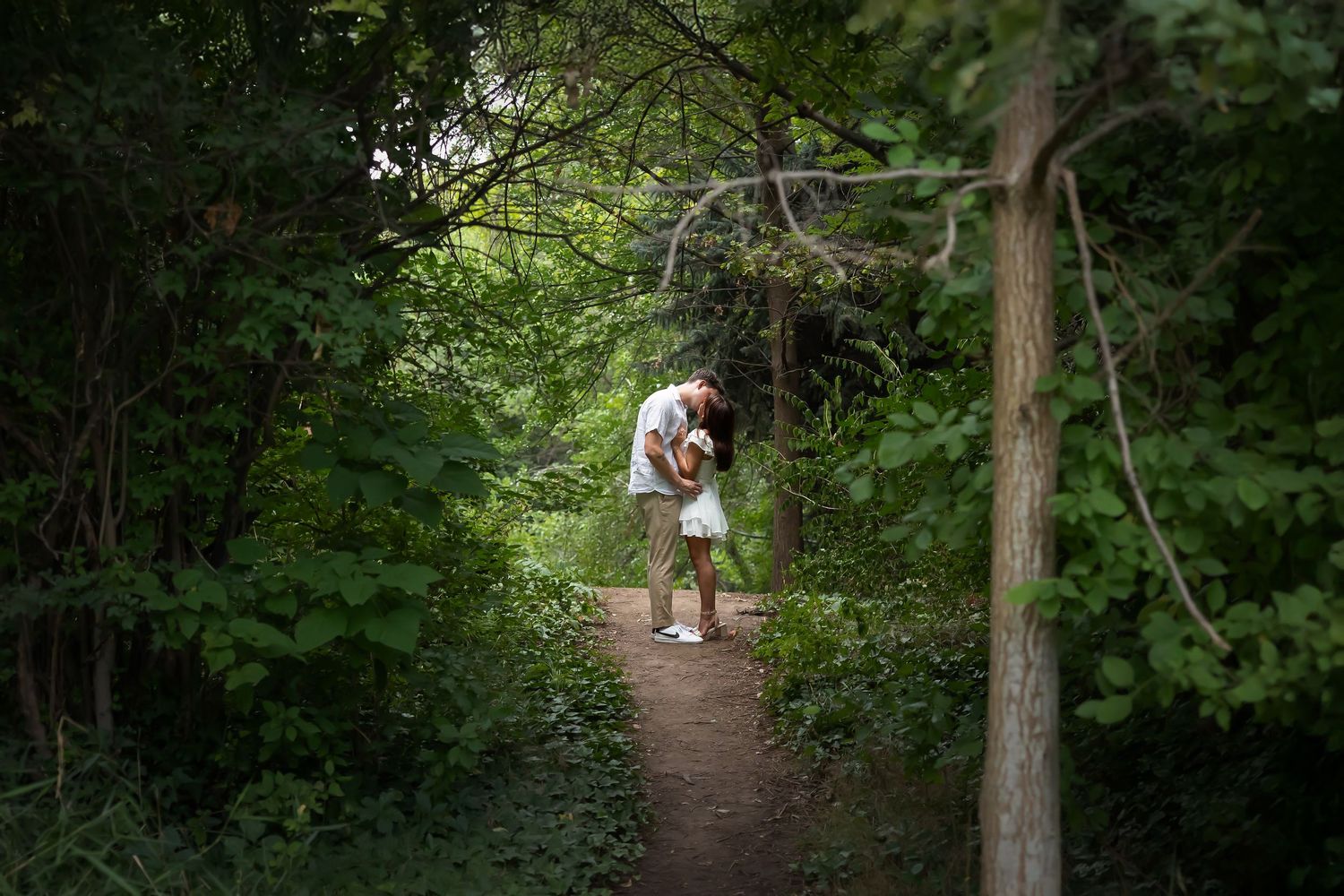 Couple kissing at top of hill in the forest. Boise wedding photographer.