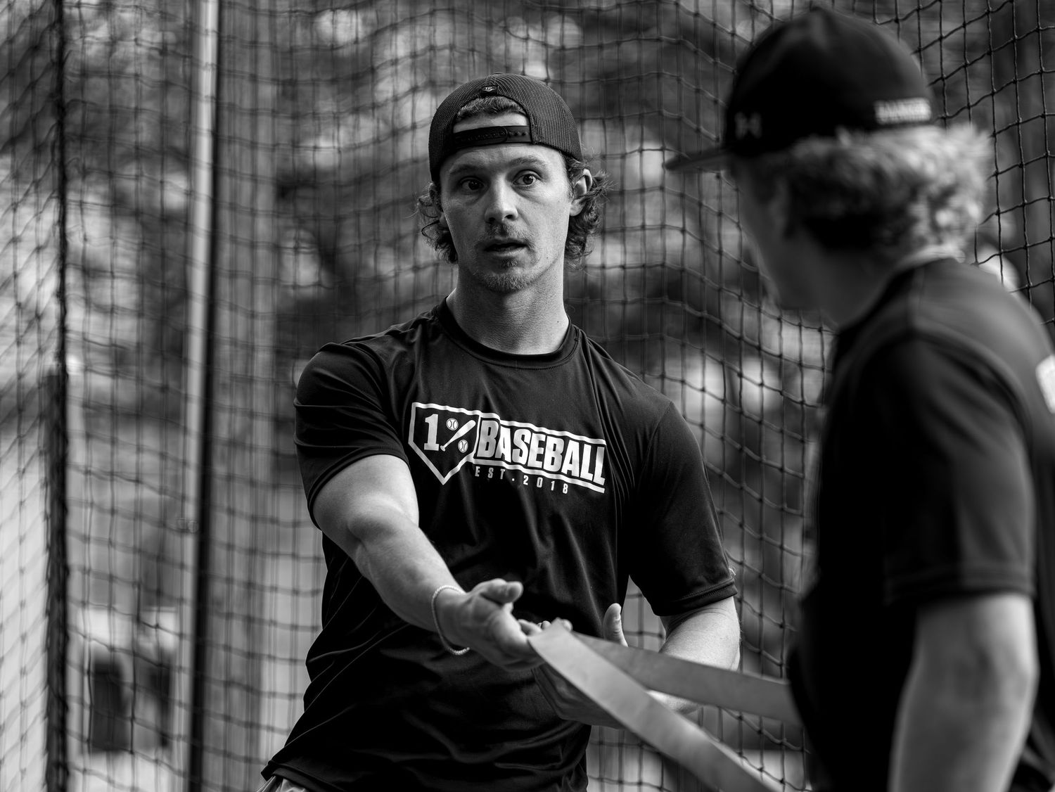 Baseball players in black uniforms having a discussion during practice.