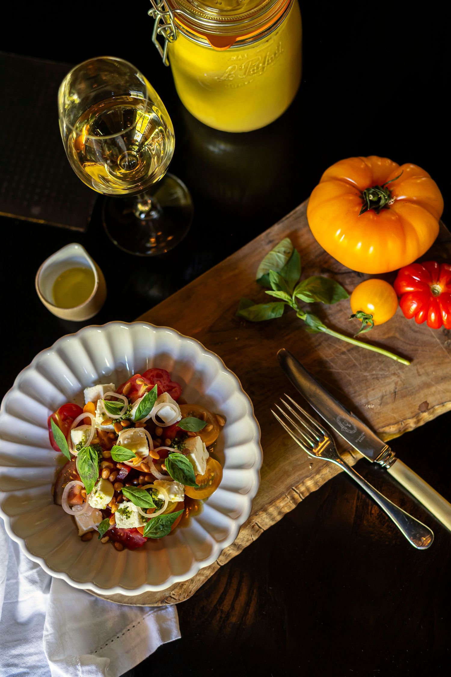 Elegantly plated appetizers with garnishes on white plates illuminated by candlelight against a rustic orange backdrop.