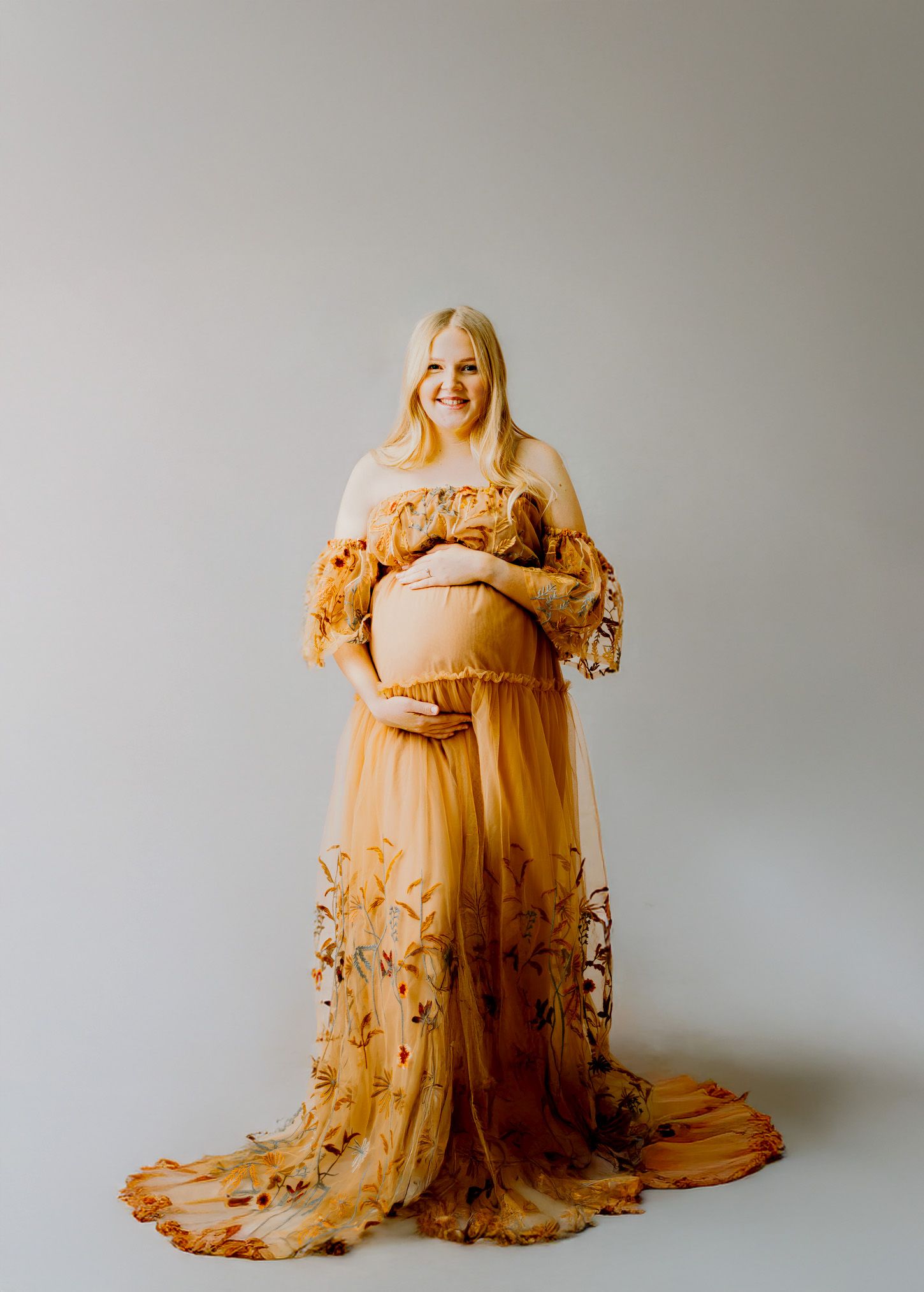 Elegant peach tulle dress with floral embroidery and bell sleeves displayed on white hanger against neutral background.