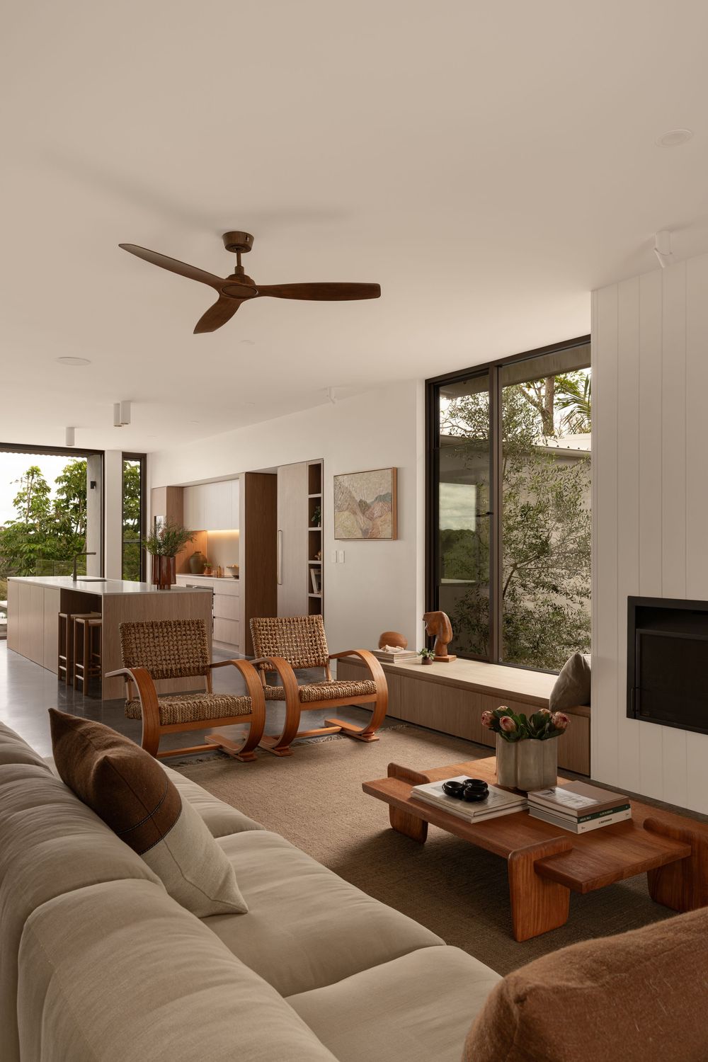 Open-plan living area with white walls, wooden accents, and comfortable seating arranged around large windows.