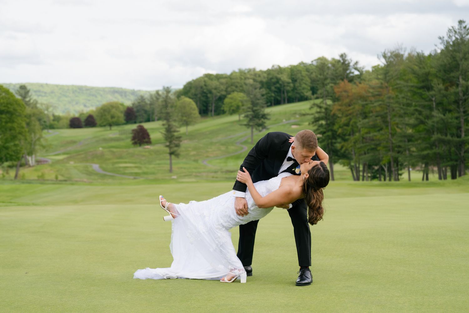 Black and white romantic wedding photo of newlyweds sharing an intimate moment outdoors.