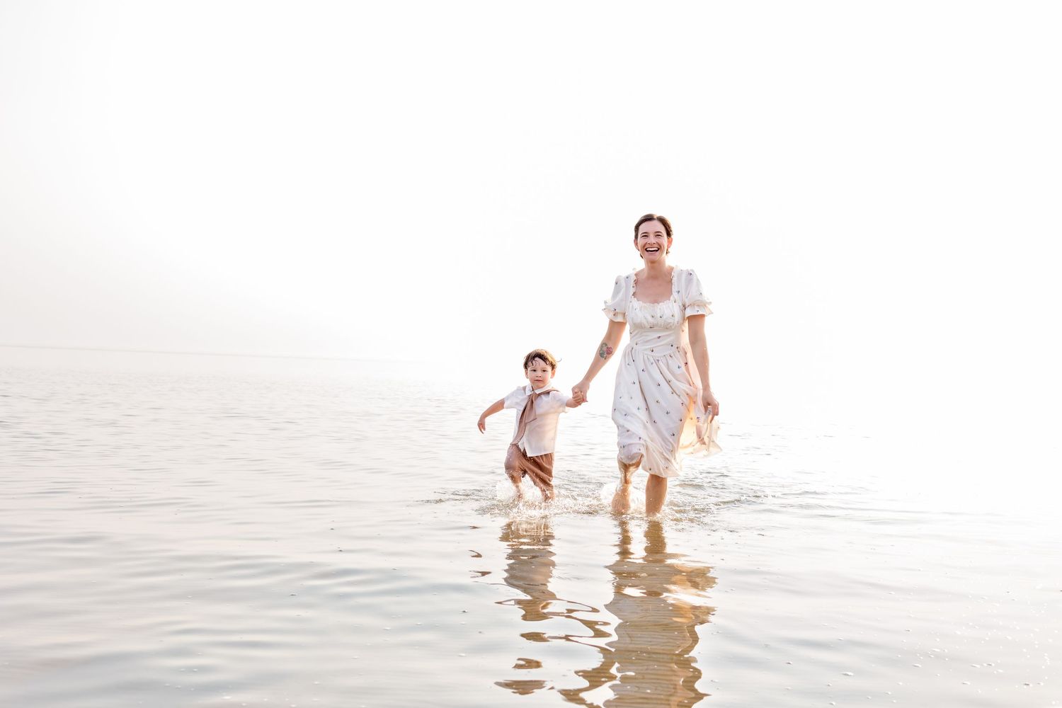 A joyful family plays together in the shallow lake water at sunset, creating splashes and cherished memories.