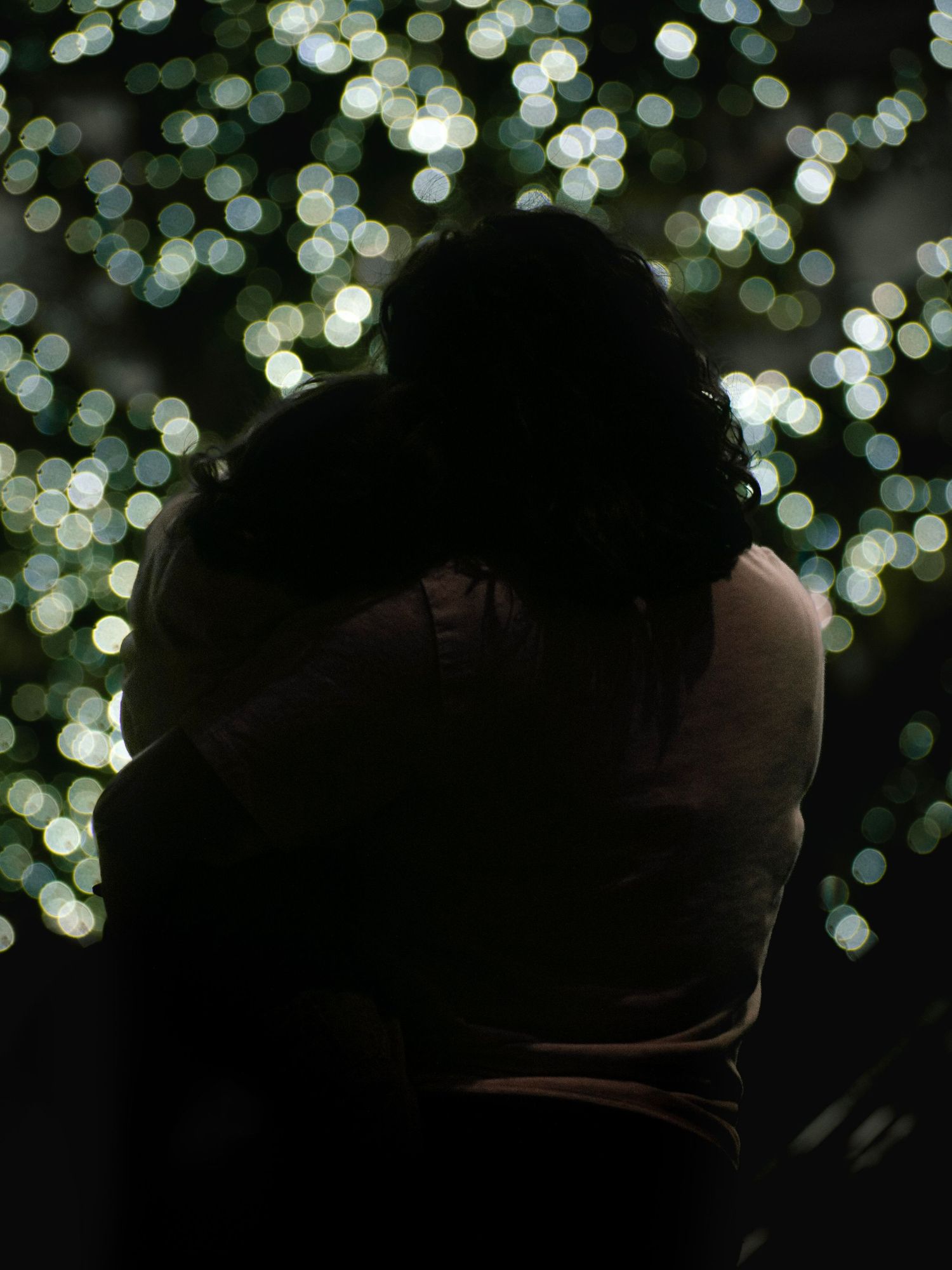 Silhouetted figures against a backdrop of soft bokeh lights creating a dreamy atmosphere.