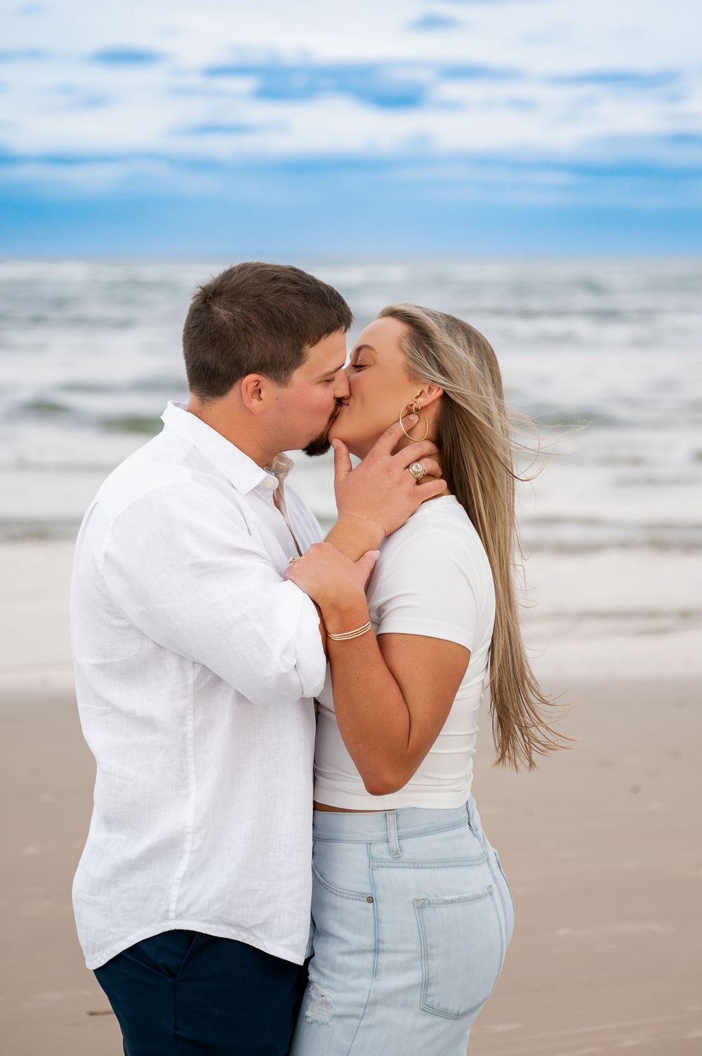 Romantic beach moment with couple sharing intimate kiss by ocean.