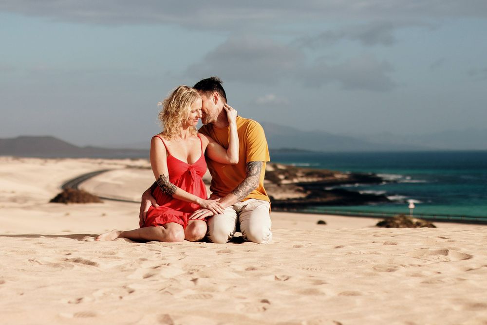Couple in summer outfits sitting together on the Corralejo dunes - Natural lifestyle photography in Fuerteventura