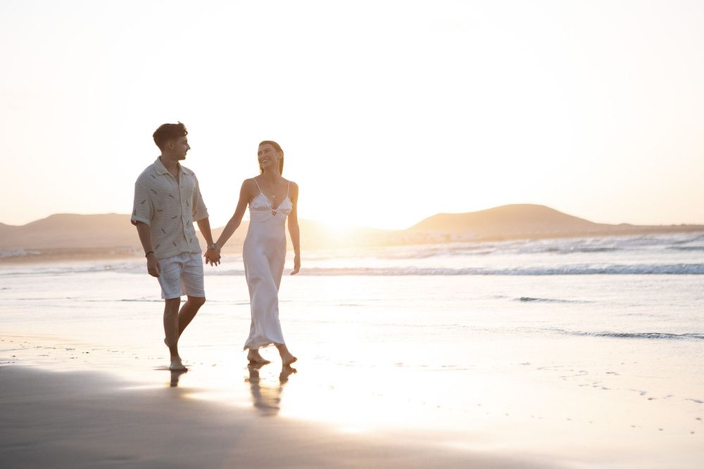 Couple walking hand in hand on a misty beach at sunset - Romantic Lanzarote wedding photography