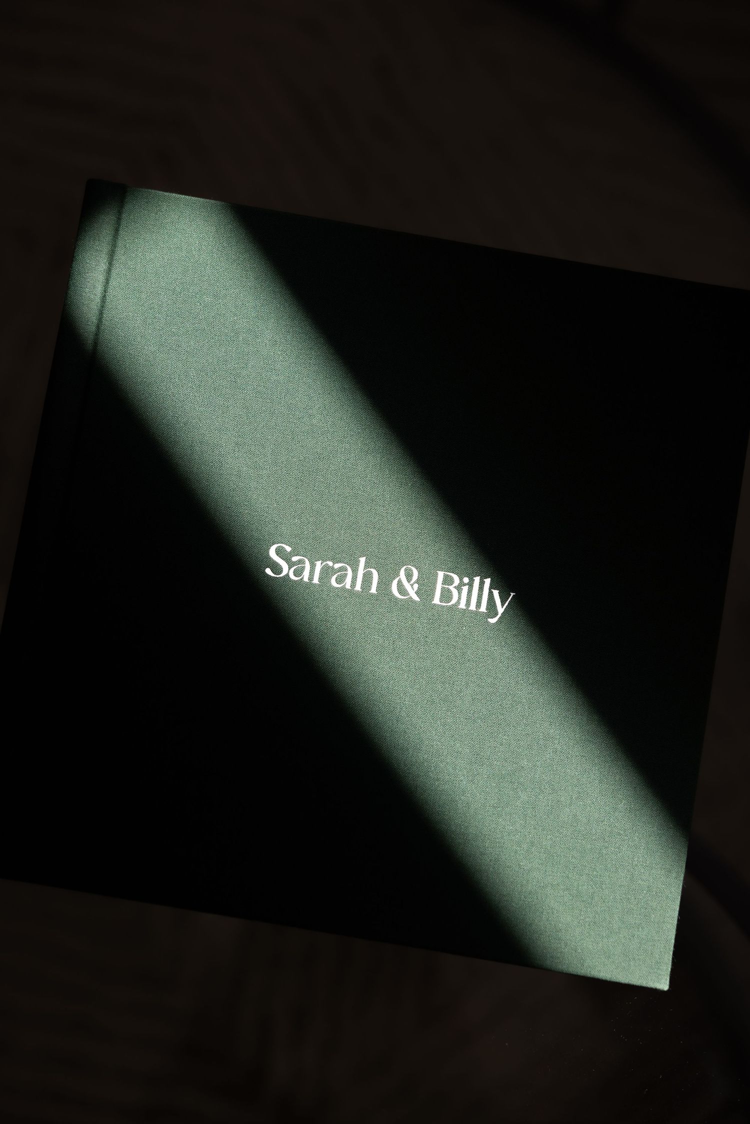 A black and white photo of text reading 'Sarah & Billy' with a diagonal beam of light across it.