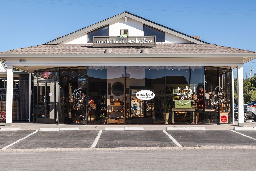 Exterior panoramic view of a traditional white country store building with covered porch and parking area.