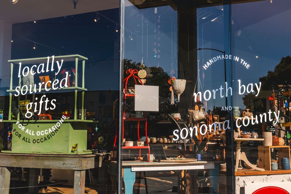 Row of illuminated storefront signs at dusk displaying local business names in North Bay and Sonoma County area.