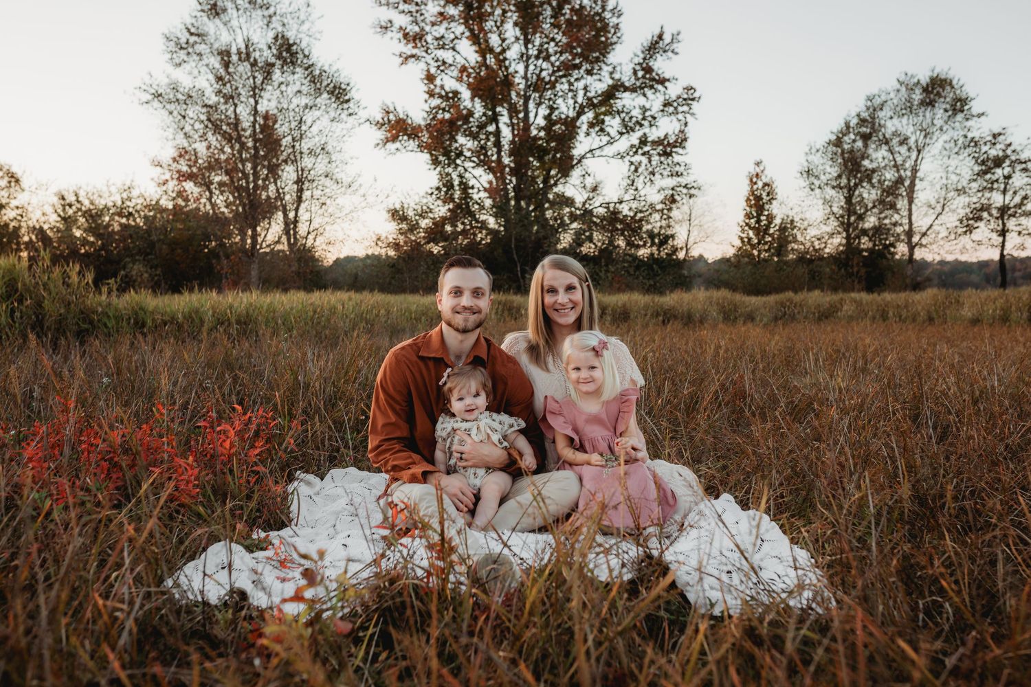 Cullman Alabama Family Photographer. Family sitting together in a rustic autumn field during golden hour.